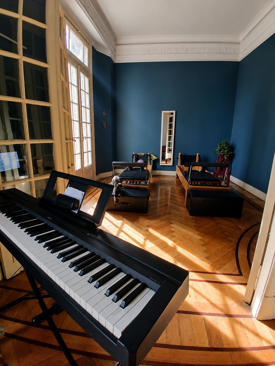 Sala de Casa Mare con reformers, piano y ventanal en una casa de época de Balvanera